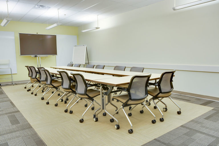A view of a smart room in a table group configuration with a tv and whiteboards
